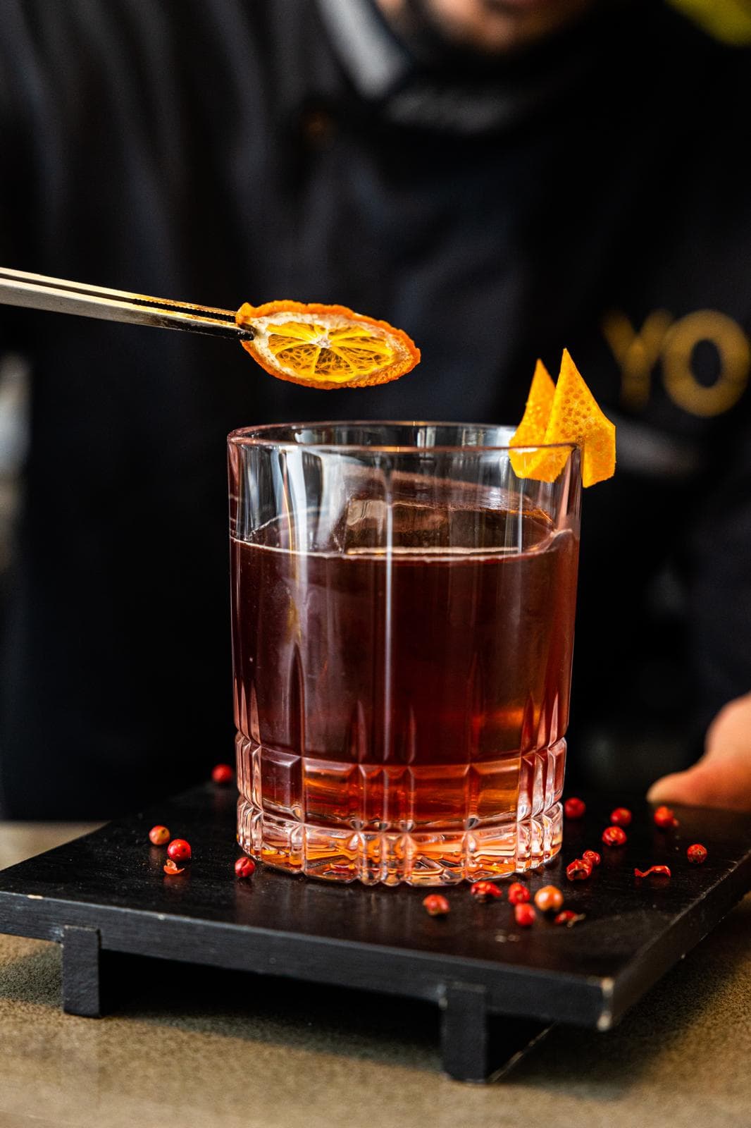 Barman GA Cocktails posiziona il twist d'arancia con la pinzetta